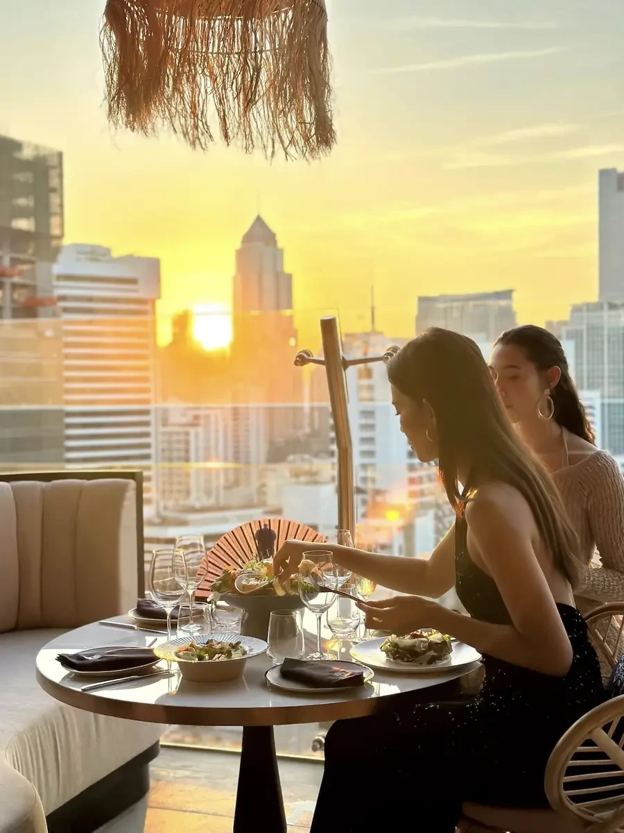 Two beautiful Thai women dining on the rooftop of Pastel Bar & Restaurant, overlooking the city of Bangkok