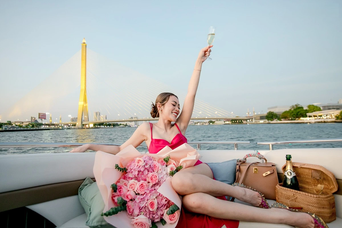Beautiful lady celebrating with a glass of Champagne on a private Yacht on the Chao Phraya river in Bangkok