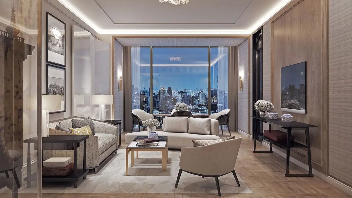 A stylish living room with beige sofas, a coffee table, and chairs, featuring large windows with a city skyline view