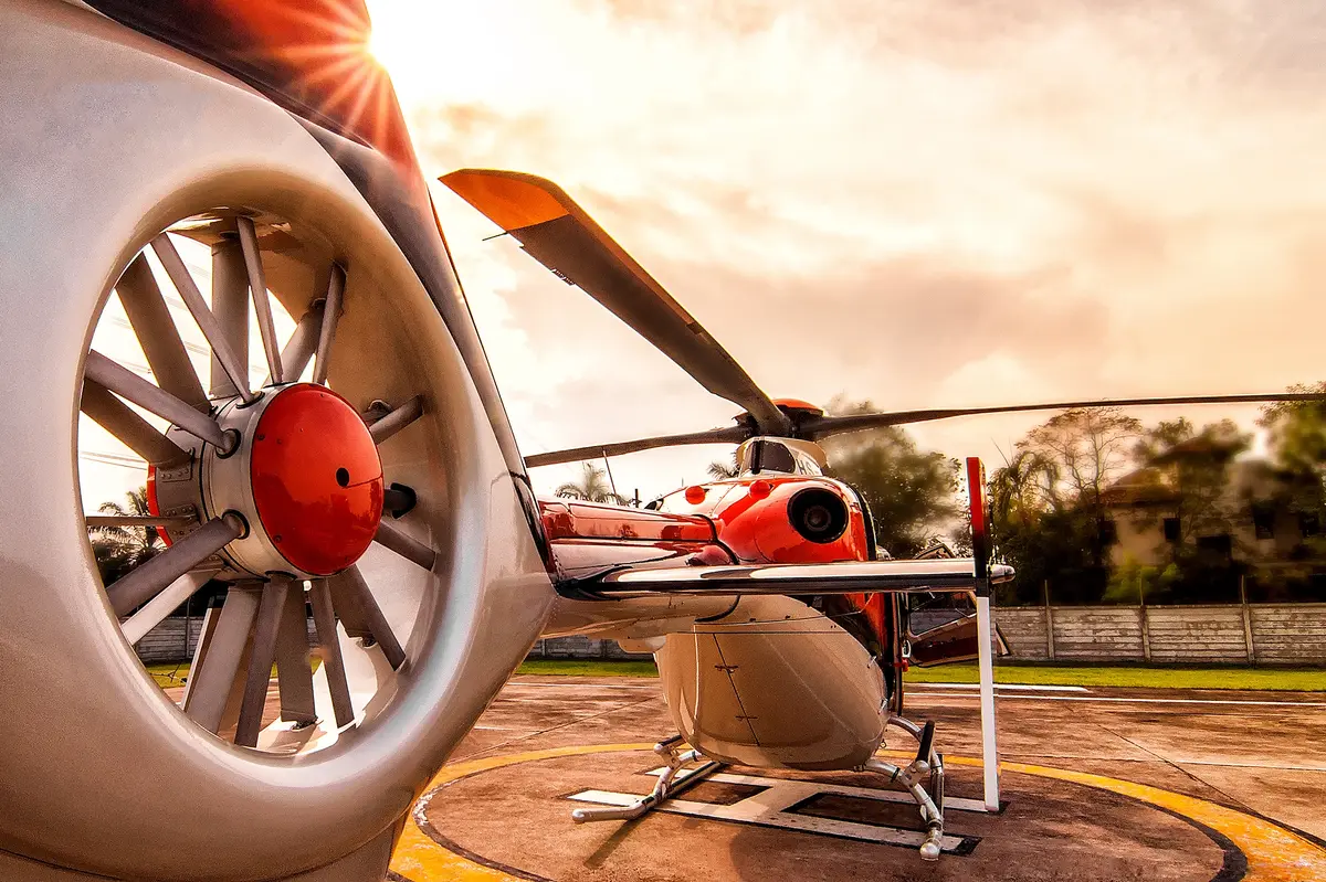Orange and white helicopter parked on a heliport